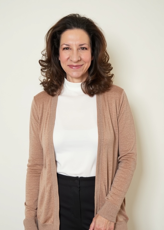 Suzanne Muller standing in a white shirt and long beige sweater